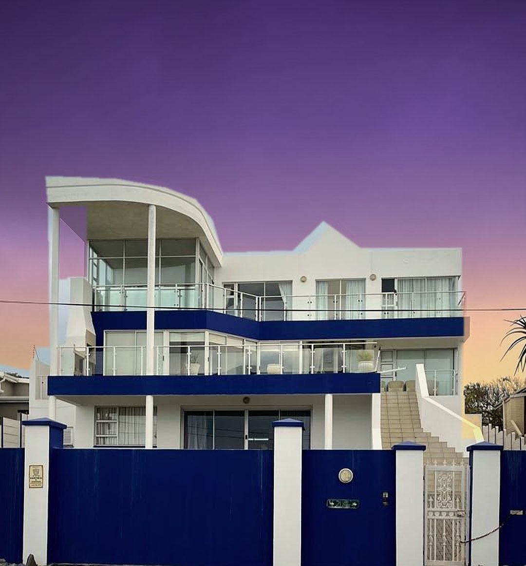 Beulah Healing and Wellness Centre at dusk: a white three-storey house with curved roof canopy, glass balconies and blue trim, facing the sea